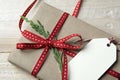 Gift box, wrapped in recycled paper, red bow and tag on wood bac Royalty Free Stock Photo