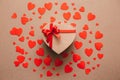 Gift box wrapped in recycled paper with red ribbon bow on background of red hearts. Royalty Free Stock Photo