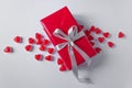 Gift-box is wrapped in red paper with silver ribbon bow. Isolated on a white background in a pile of jelly hearts. Royalty Free Stock Photo