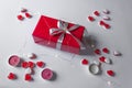 Gift box wrapped in red paper with silver ribbon bow. White background with jelly hearts, candles and lights. Holidays. Royalty Free Stock Photo