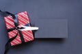 Gift box wrapped in red striped paper and tied with black bow and black tags. Royalty Free Stock Photo