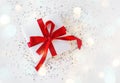 Gift box wrapped in white paper with a red bow on festive light background Royalty Free Stock Photo