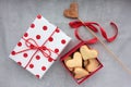 Gift box in wrapping paper with red polka dot pattern and heart shaped cookies on gray concrete background. Royalty Free Stock Photo