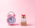 Gift boxes with alarm clock on pink background. Christmas or New Year minimal concept Royalty Free Stock Photo