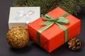 Gift boxes, ball, cone and fir tree branch on black background
