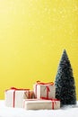 Gift boxes, Christmas tree on table and yellow background. Royalty Free Stock Photo