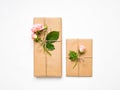 Gift boxes in eco paper on white background. Presents decorated with roses. Holiday concept, top view, flat lay Royalty Free Stock Photo