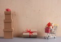 Gift boxes piles and shopping cart on wooden background