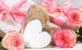 Gift boxes with pink polka dots bows, gentle peach color roses, empty white wooden heart. Close up.