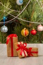 Gift boxes with red bows and Christmas tree with twinkling party lights and toy balls Royalty Free Stock Photo