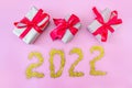 Gift boxes with ribbon on a pink background and the inscription 2022