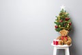 Gift boxes, teddy bear and small decorated Christmas tree on stool chair Royalty Free Stock Photo
