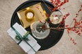 Gift boxes tied with emerald ribbon on a black coffee table, a candle and branches with red berries in a vase Royalty Free Stock Photo