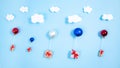 Gift boxes tied with red ribbons fly under the clouds on white, red, blue Christmas balls like balloons. Blue background Royalty Free Stock Photo