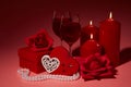 Gift boxes, two glasses with wine, burning candles, red roses and hearts on red background. Valentine`s day. Wedding day Royalty Free Stock Photo