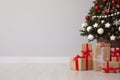 Gift boxes under decorated Christmas tree near grey wall. Space for text Royalty Free Stock Photo