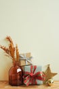 Gift boxes, vase of dry flower, christmas ornament on wooden table. ivory wall background. winter christmas, copy space