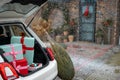 Gift boxes in vehicle trunk in front of a house decorated for winter holidays Royalty Free Stock Photo