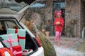 Gift boxes in vehicle trunk in front of a house decorated for winter holidays Royalty Free Stock Photo