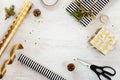 Gift boxes wrapped in black and white striped and goden dotted paper with, pine, cones, candle and wrapping materials on a white w