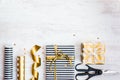 Gift boxes wrapped in black and white striped and golden dotted paper and wrapping materials on a white wood old background. Empty Royalty Free Stock Photo