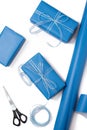 Gift boxes wrapped in blue paper and content of a workspace composed on white background. Gift packing concept. Flat lay