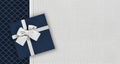 Gift card with gift box with ribbon and bow isolated on elegant blue and gray fabrics background, top view and copy space template Royalty Free Stock Photo