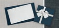 Gift card and gift box with ribbon and bow isolated on elegant blue and grey fabrics background, top view and copy space template Royalty Free Stock Photo