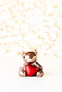 Gift card with chocolate bear holding red heart on golden background of christmas lights bokeh. Mockup for decorative Royalty Free Stock Photo