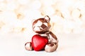 Gift card with chocolate bear holding red heart on golden background of christmas lights bokeh. Mockup for decorative Royalty Free Stock Photo