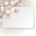 Gift card with peral gold ribbon on a beige background and snowflakes. Royalty Free Stock Photo