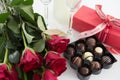 Gift, chocolate box, roses and champagne bottle on white background