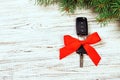 Gift for christmas car keys. Close-up view of car keys with red bow as present on wooden rustic vintage background Royalty Free Stock Photo