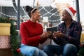 Gift, couple and christmas celebration on sofa by happy, excited and loving people sharing joy, cheer and giving in Royalty Free Stock Photo