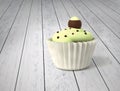 Gift cupcake with pistachio cream and chocolate balls on cold white wood