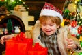 Gift emotions. Kid having fun near Christmas tree indoors. Funny kid holding Christmas gift. Cute little kids