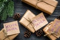 Gift exchange. Boxes with note Santa Secret near spruce branch on dark wooden background top view