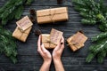 Gift exchange. Hands hold box with note Santa Secret near spruce branch on dark wooden background top view