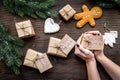 Gift exchange. Hands hold box with note Santa Secret near spruce branch and gingerbread cookies on dark wooden