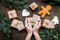 Gift exchange. Hands hold box with note Santa Secret near spruce branch and gingerbread cookies on dark wooden