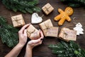 Gift exchange. Hands hold box with note Santa Secret near spruce branch and gingerbread cookies on dark wooden