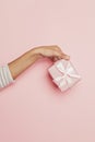 Gift in female hand on pink background. Abstract holiday present concept Royalty Free Stock Photo