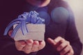 gift giving,man hand holding a gift box in a gesture of giving.blured background,bokeh effect Royalty Free Stock Photo