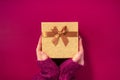 Gift with golden bow on purple background. Top view. Festive backdrop for holidays: Birthday, Valentines day, Christmas, New Year Royalty Free Stock Photo