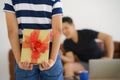 Gift in hand of kid hiding behind want to make surprise giving to father