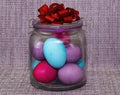 A gift jar with colored eggs and a red bow for Easter. Royalty Free Stock Photo