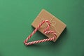 Gift Kraft Brown Color Box and Candy Canes Red and White in Heart Shape Lies on the Green Background, View From the Top. For your Royalty Free Stock Photo