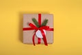 Gift kraft square box with a red ribbon on a yellow background