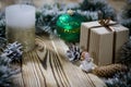 A gift lays on a wooden table next to a candle, cones and an angel against the background of Christmas decorations Royalty Free Stock Photo