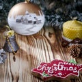 A gift lays on a wooden table next to a candle, cones and an angel against the background of Christmas decorations Royalty Free Stock Photo